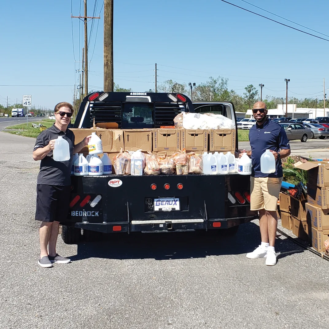 Two men pose in front of emergency assistance supplies.