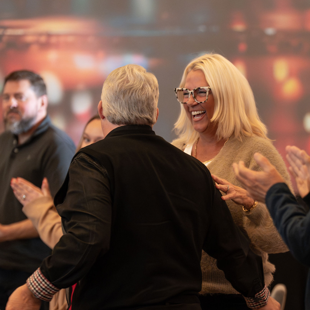 A cheerful woman receiving accolades from a group of her co-workers