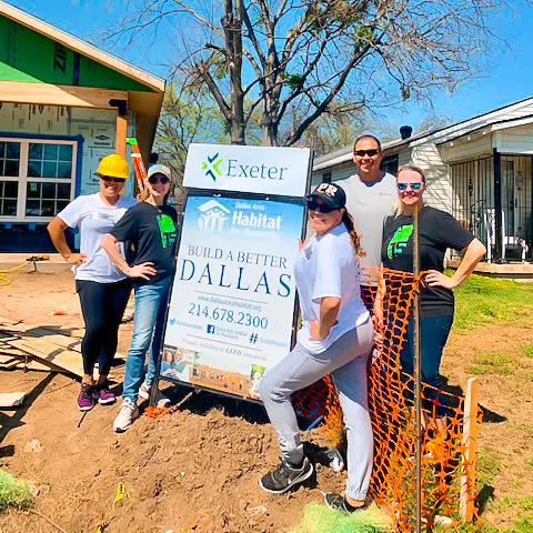 Exeter members pose in front of a Habitat for Humanity sign.